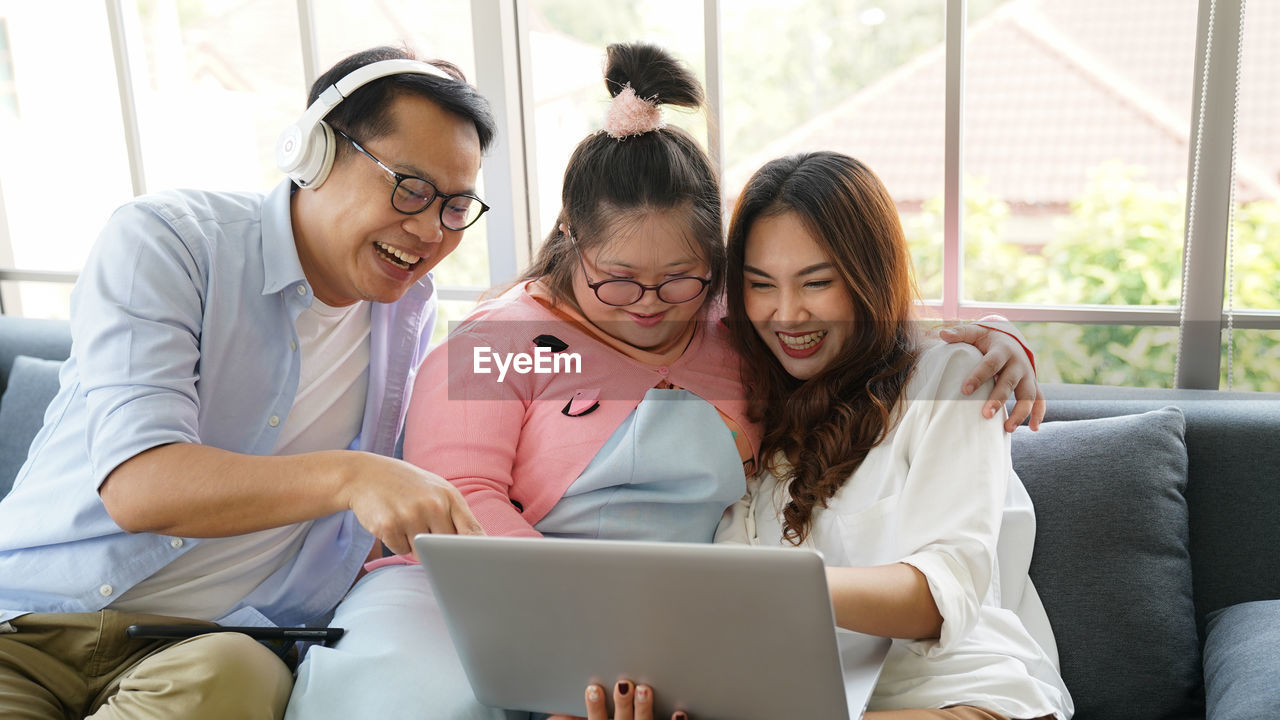 Downs syndrome sitting with home tutor using laptop for lesson at home. family using laptop at home