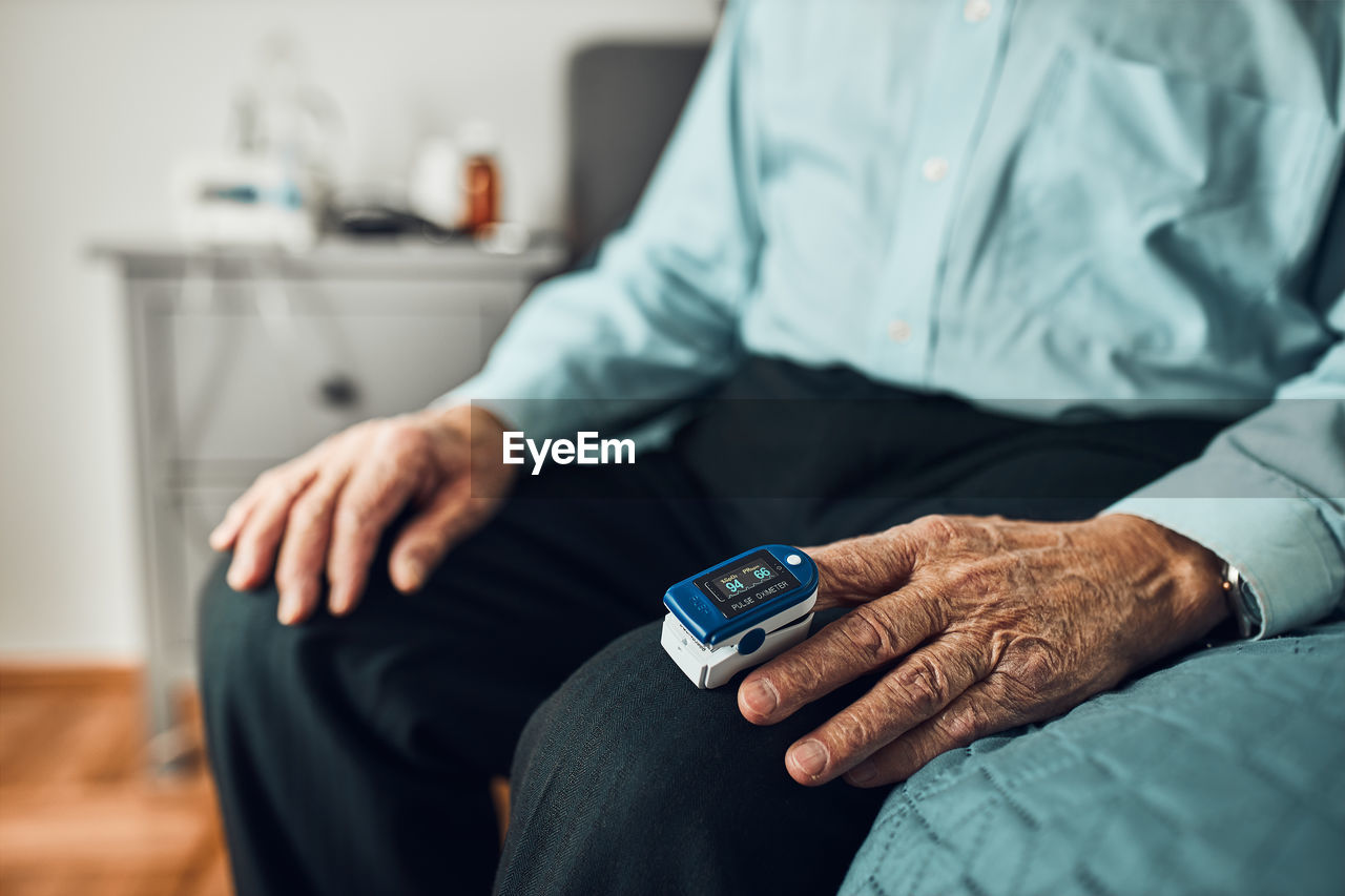 Senior man measuring the degree of oxygen saturation using pulse oximeter. checking health condition