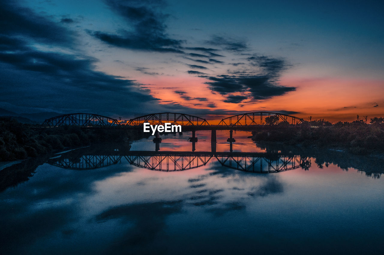 Bridge over water against sky at sunset