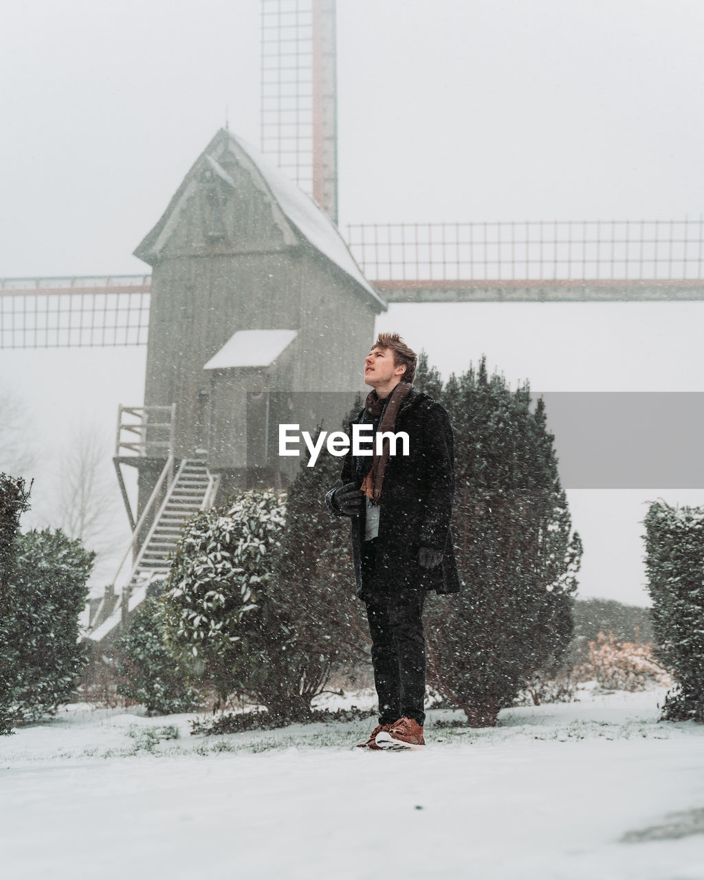 WOMAN STANDING ON SNOW COVERED TREE