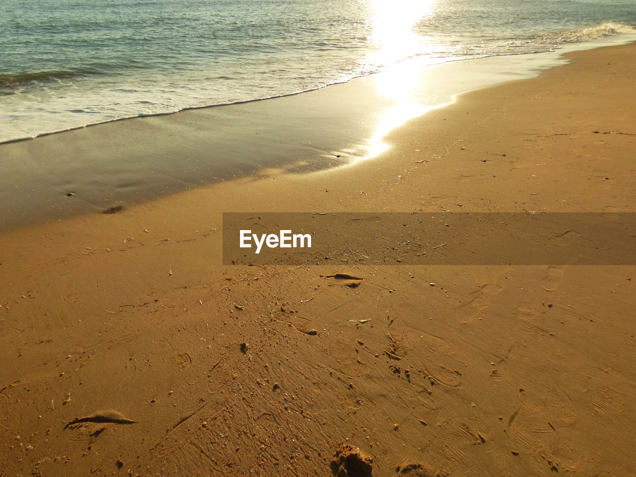 HIGH ANGLE VIEW OF FOOTPRINTS ON SAND AT BEACH AGAINST SKY