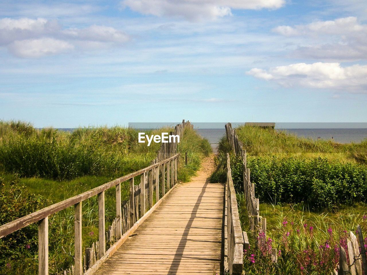 Boardwalk on beach against sky