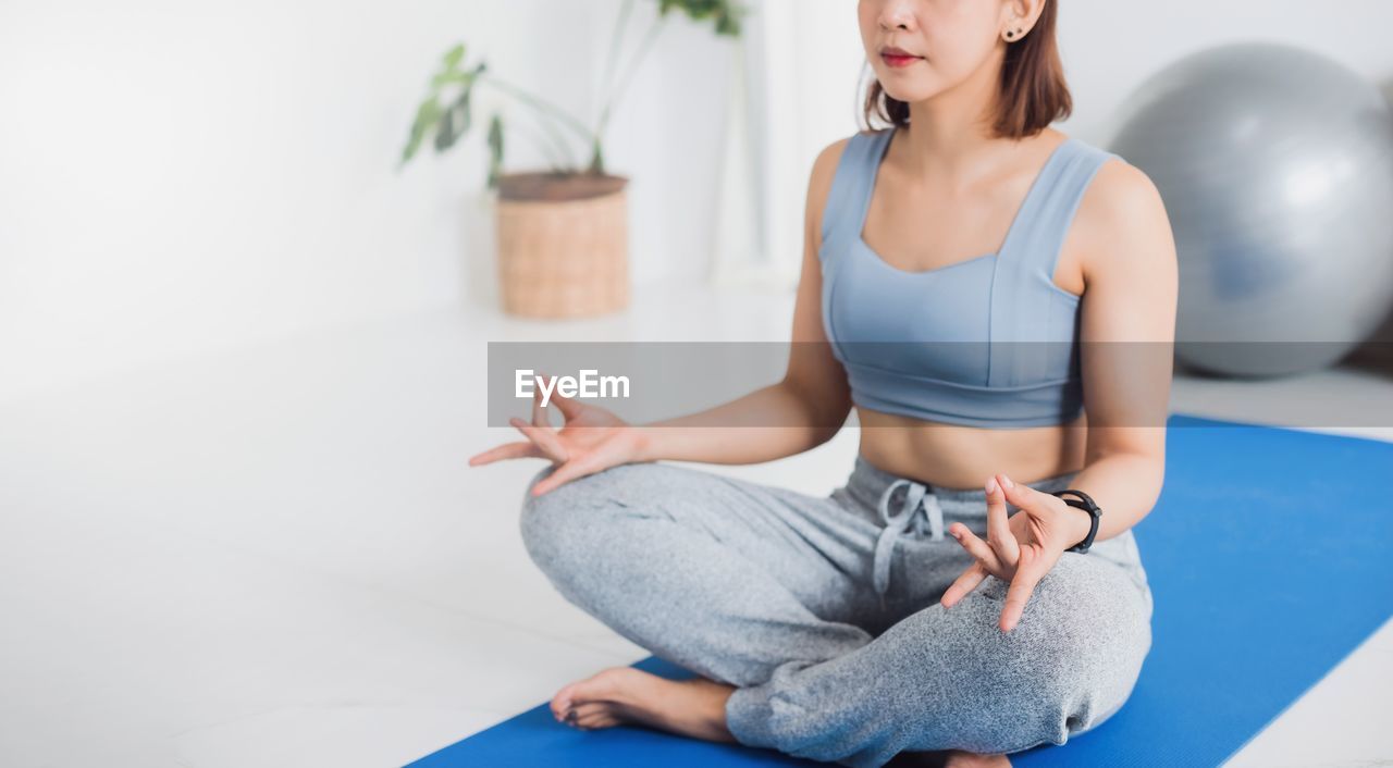 MIDSECTION OF WOMAN SITTING ON SOFA