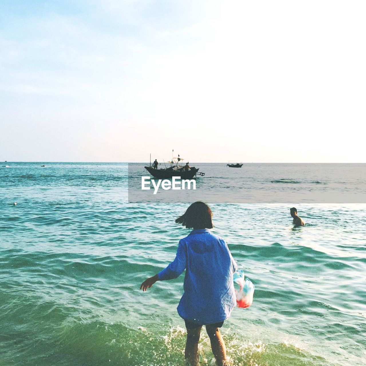 Rear view of woman walking on shore at beach against sky