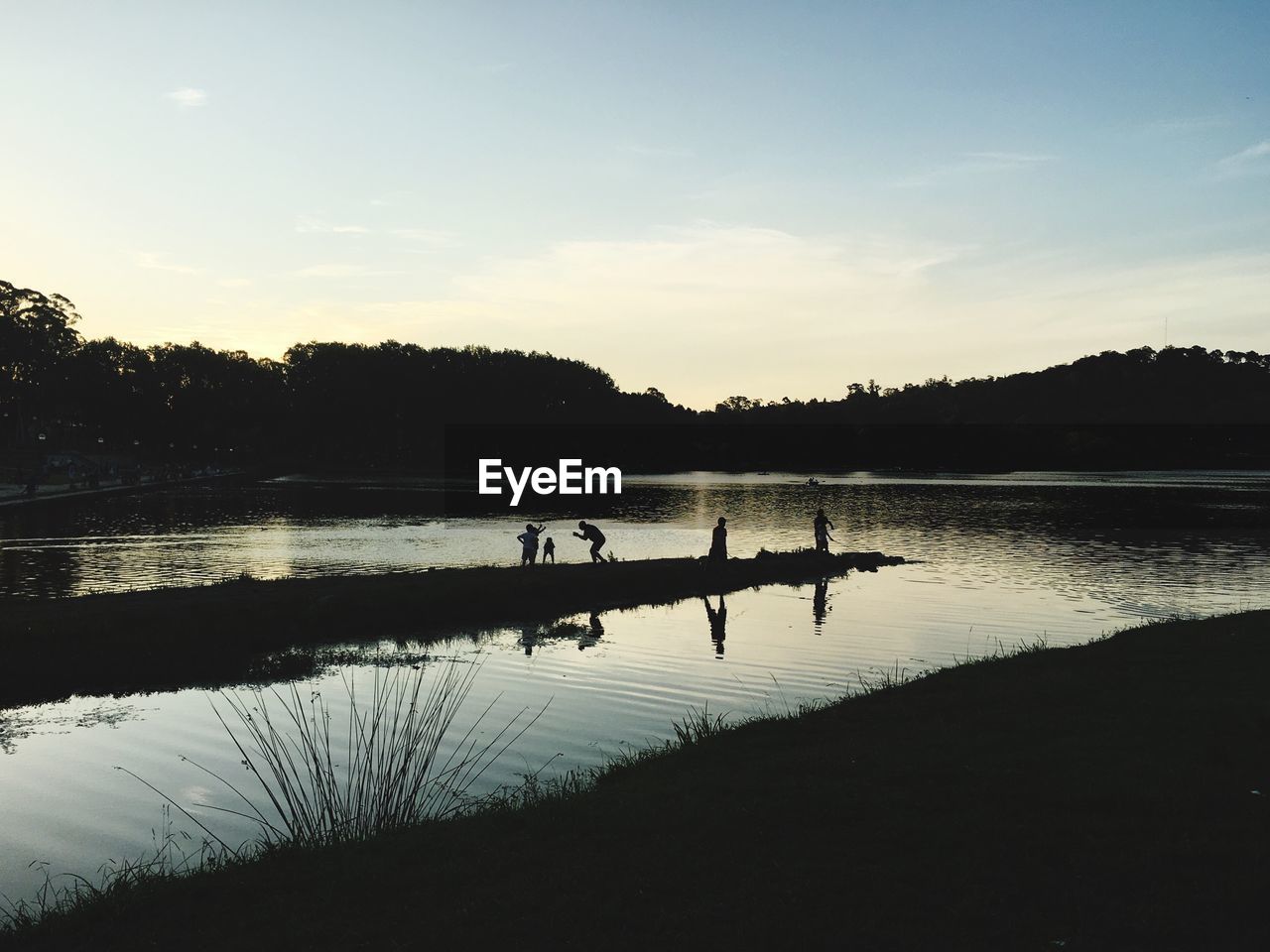 SILHOUETTE OF TREES IN LAKE AT SUNSET