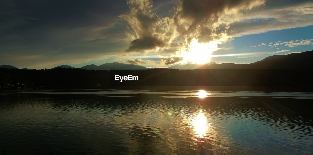 SCENIC VIEW OF LAKE BY SILHOUETTE MOUNTAINS AGAINST SKY AT SUNSET