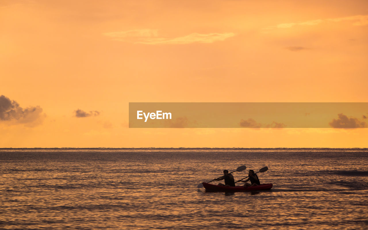 Silhouette people in boat on sea against sky during sunset