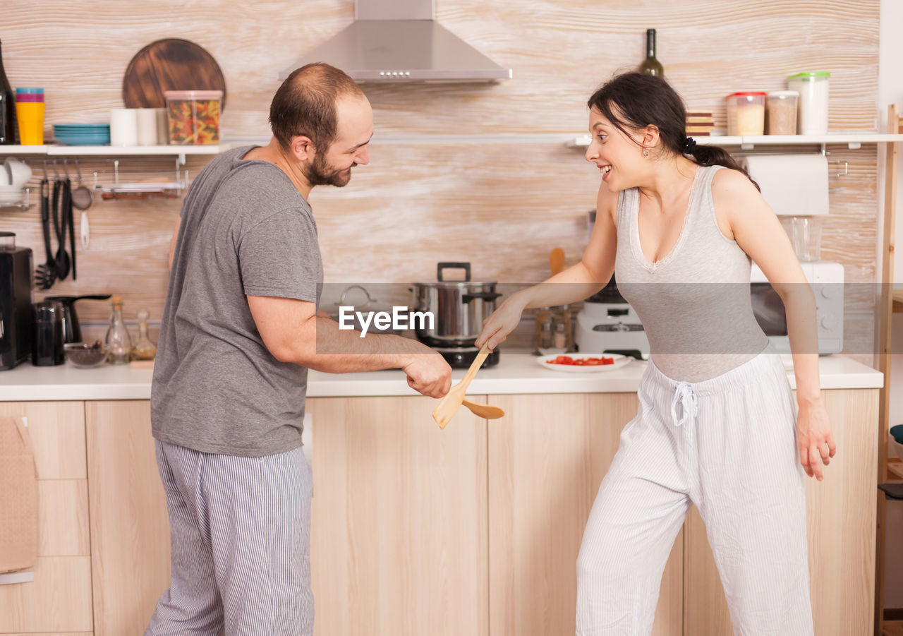 YOUNG COUPLE STANDING ON SOFA AT HOME