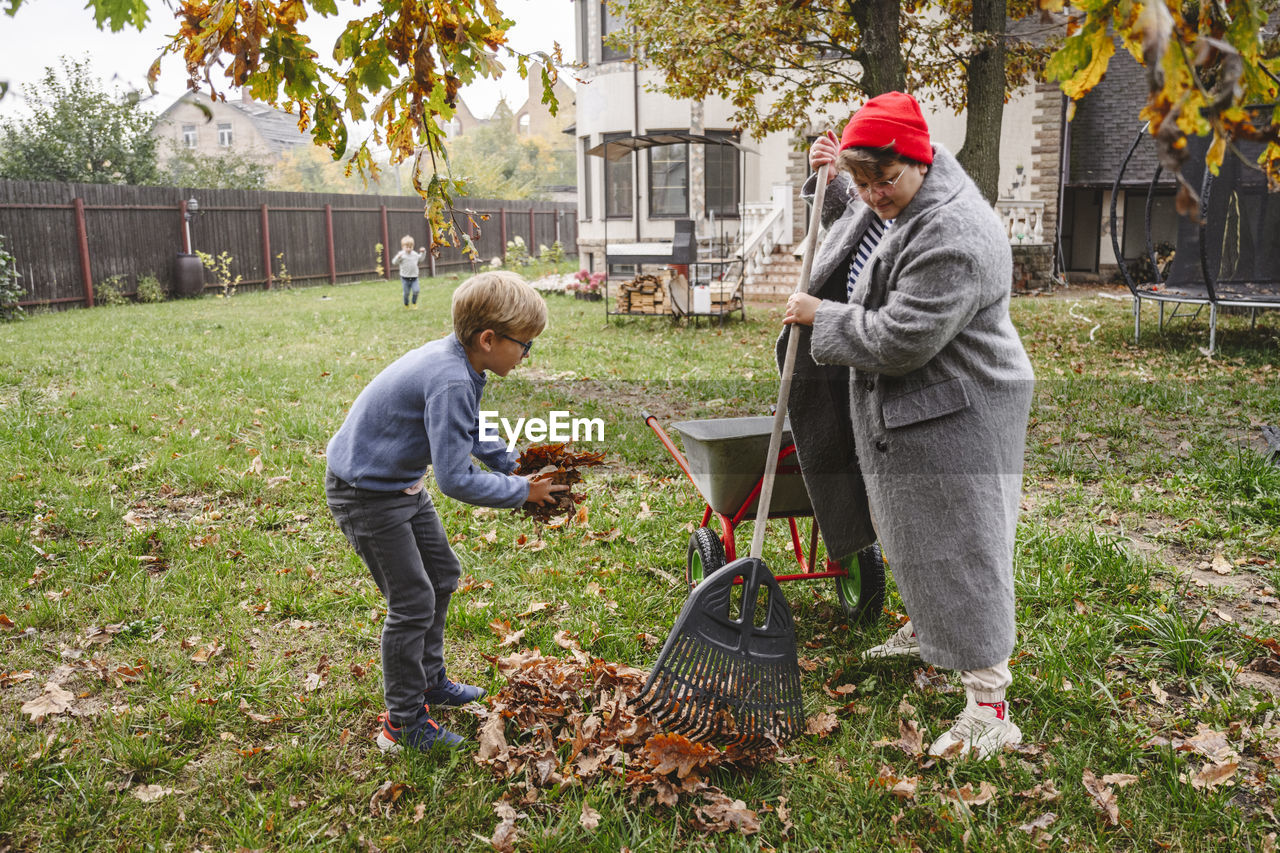 Mother with son raking dry leaves in back yard