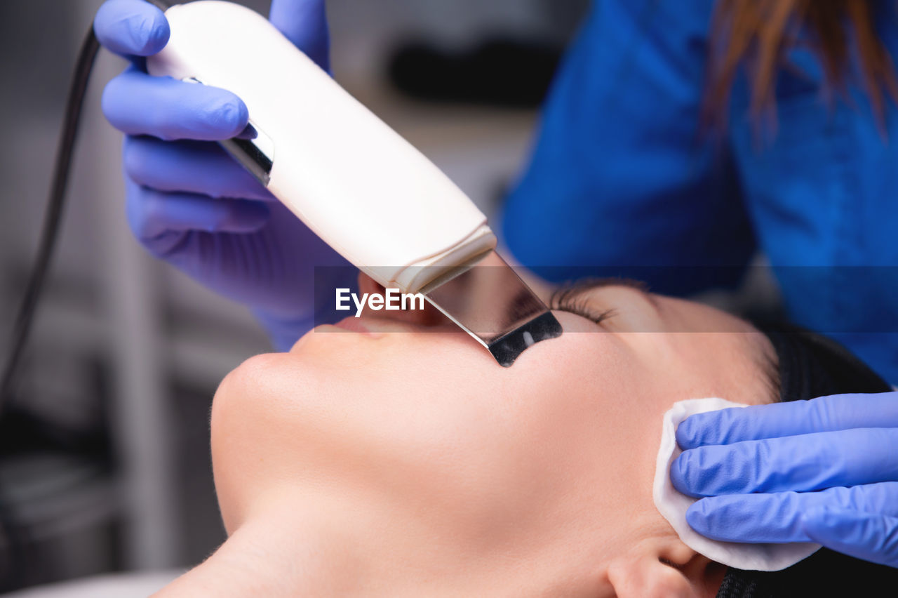 An ordinary, not beautiful european woman receives ultrasonic facial peeling in a spa. close-up