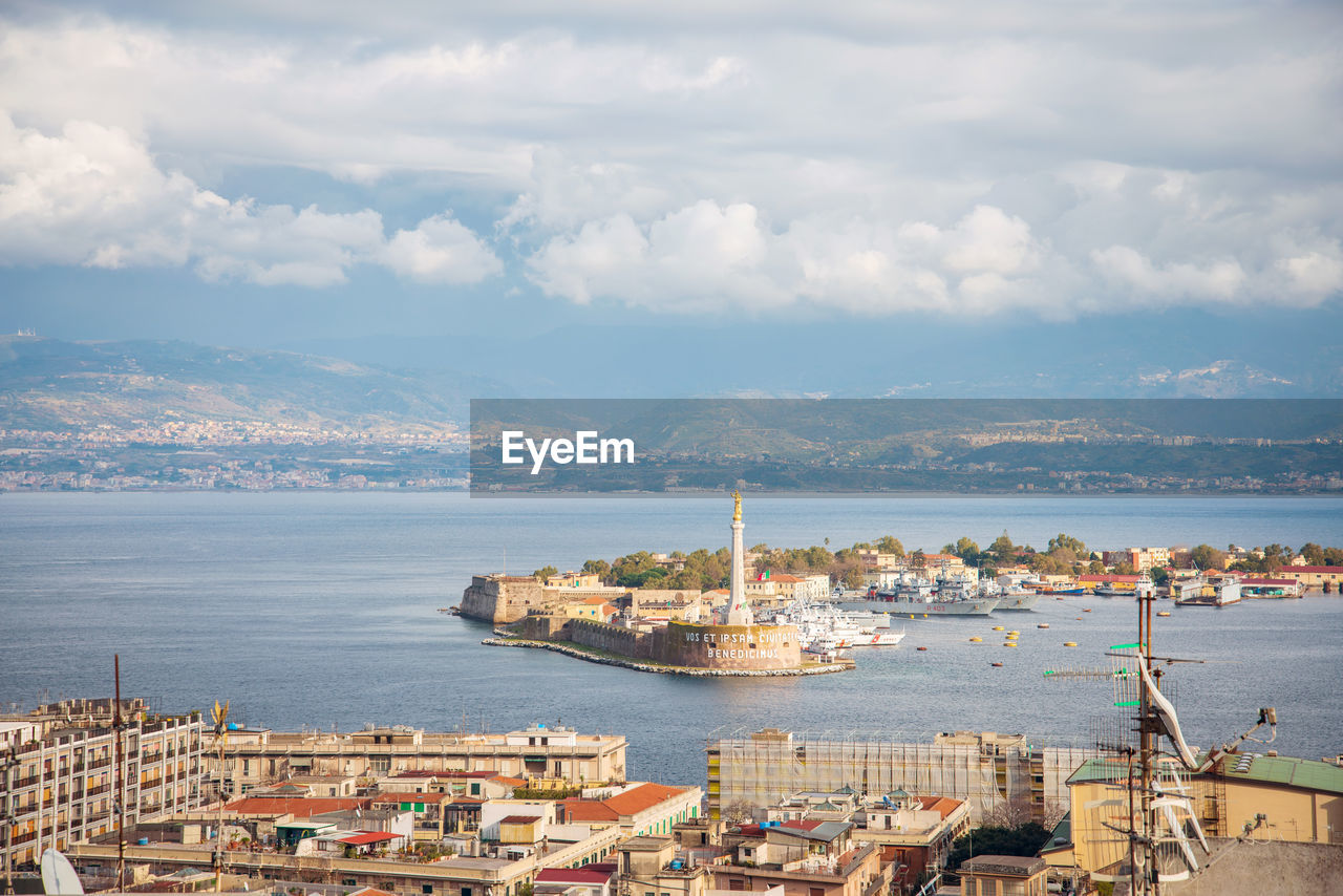 Aerial view of buildings by sea against sky