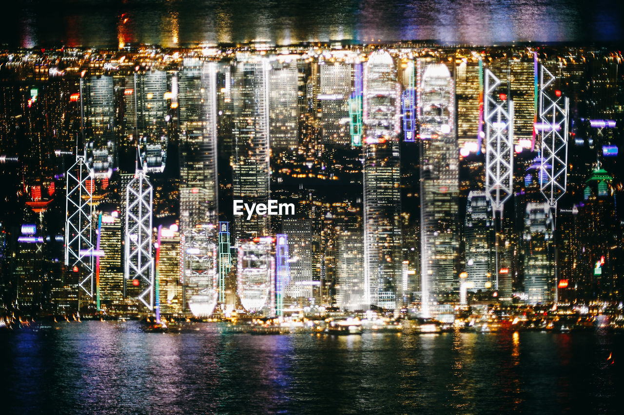 River against illuminated buildings in city at night