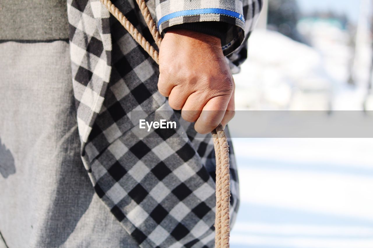 Midsection of man holding rope