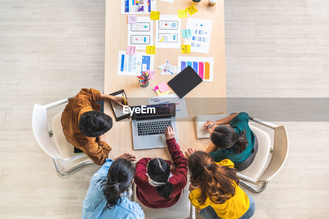 High angle view of colleagues discussing on table in office