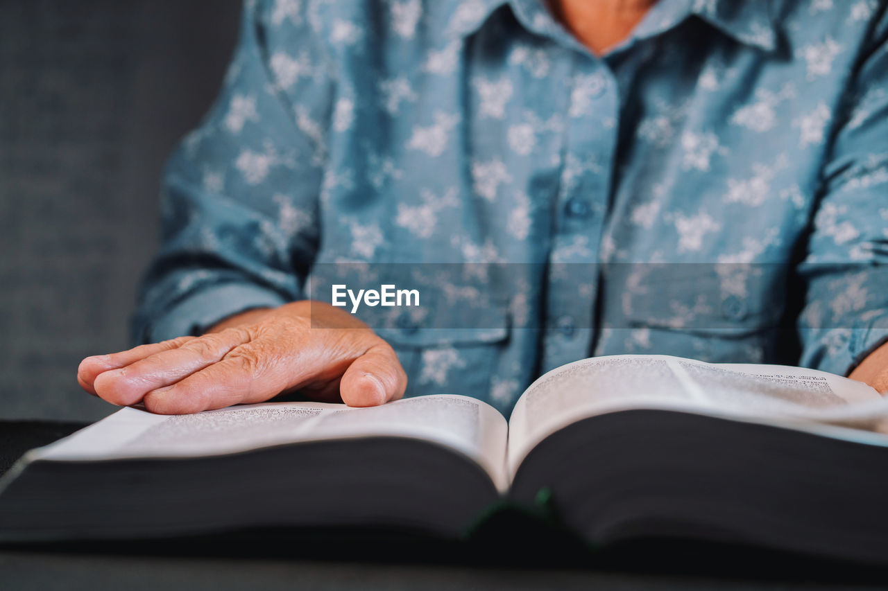 Midsection of woman reading book at home