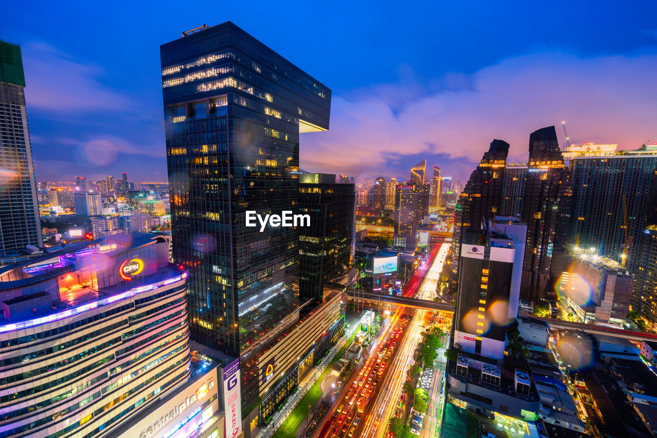 ILLUMINATED MODERN BUILDINGS AGAINST SKY AT NIGHT