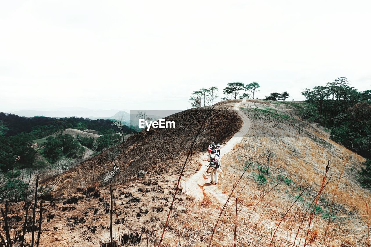 High angle view of hikers hiking on mountain against clear sky