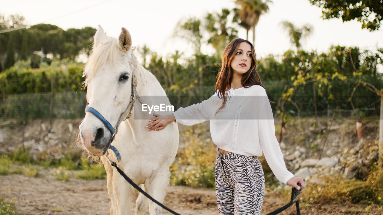 portrait of smiling young woman standing with horse