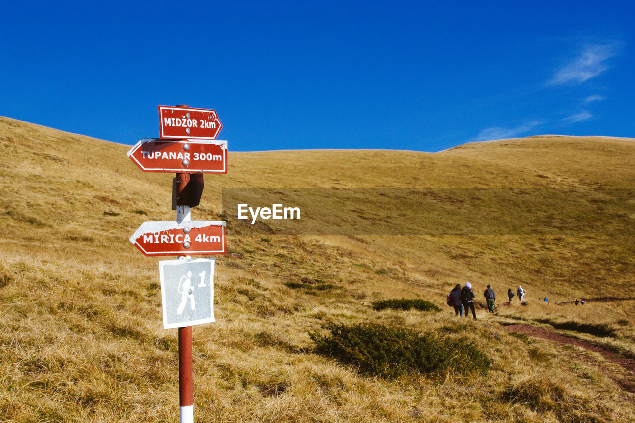 Directional sign on grassy field against mountains