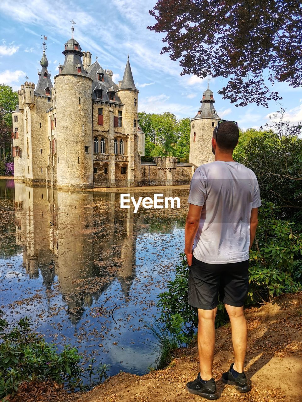water, architecture, built structure, rear view, nature, building exterior, men, full length, building, adult, sky, travel destinations, tree, plant, tourism, travel, day, casual clothing, standing, religion, outdoors, history, one person, lifestyles, cloud, the past, vacation, city, clothing, reflection, tourist, leisure activity, river, trip, waterway, place of worship