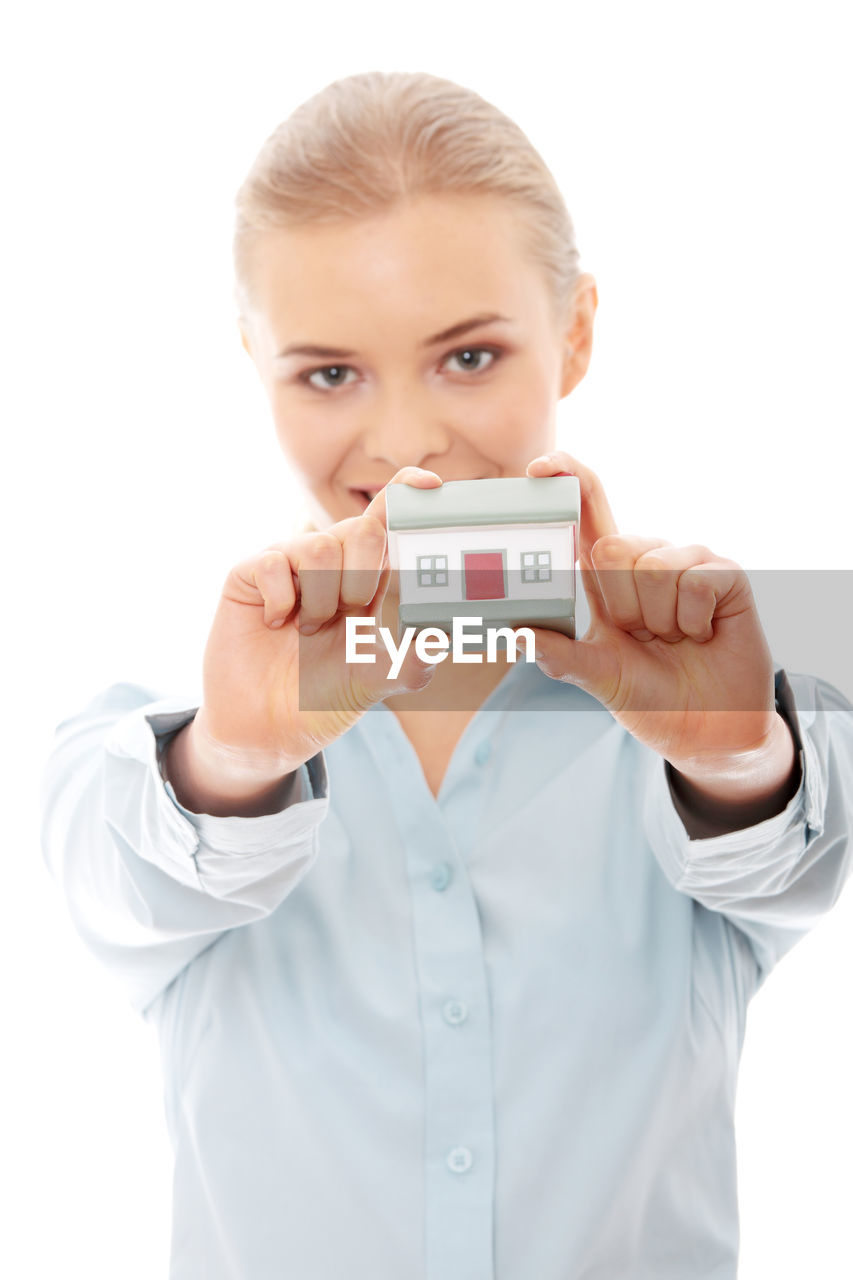 Portrait of real estate agent with model home standing against white background