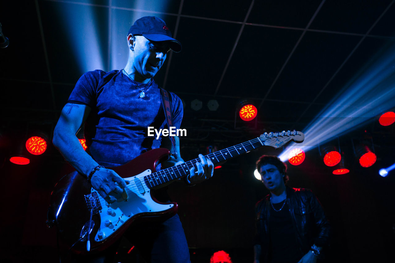 MAN PLAYING GUITAR AT ILLUMINATED CONCERT