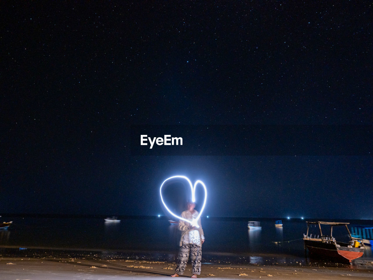 night, star, astronomy, space, illuminated, light, sky, one person, darkness, water, long exposure, nature, beach, standing, galaxy, sea, full length, land, glowing, beauty in nature, outdoors, motion, scenics - nature, arts culture and entertainment, men, childhood, copy space, space and astronomy