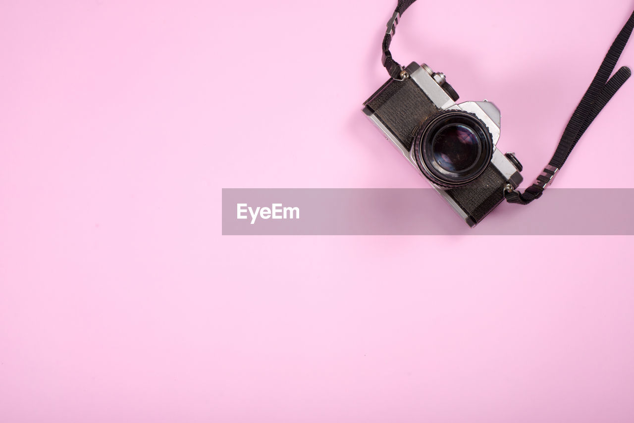 HIGH ANGLE VIEW OF CAMERA AND PINK BOTTLE