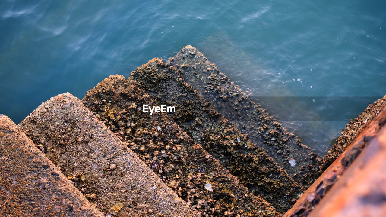 Concrete stairway old fishing port's with barnacle reef and sea water background.