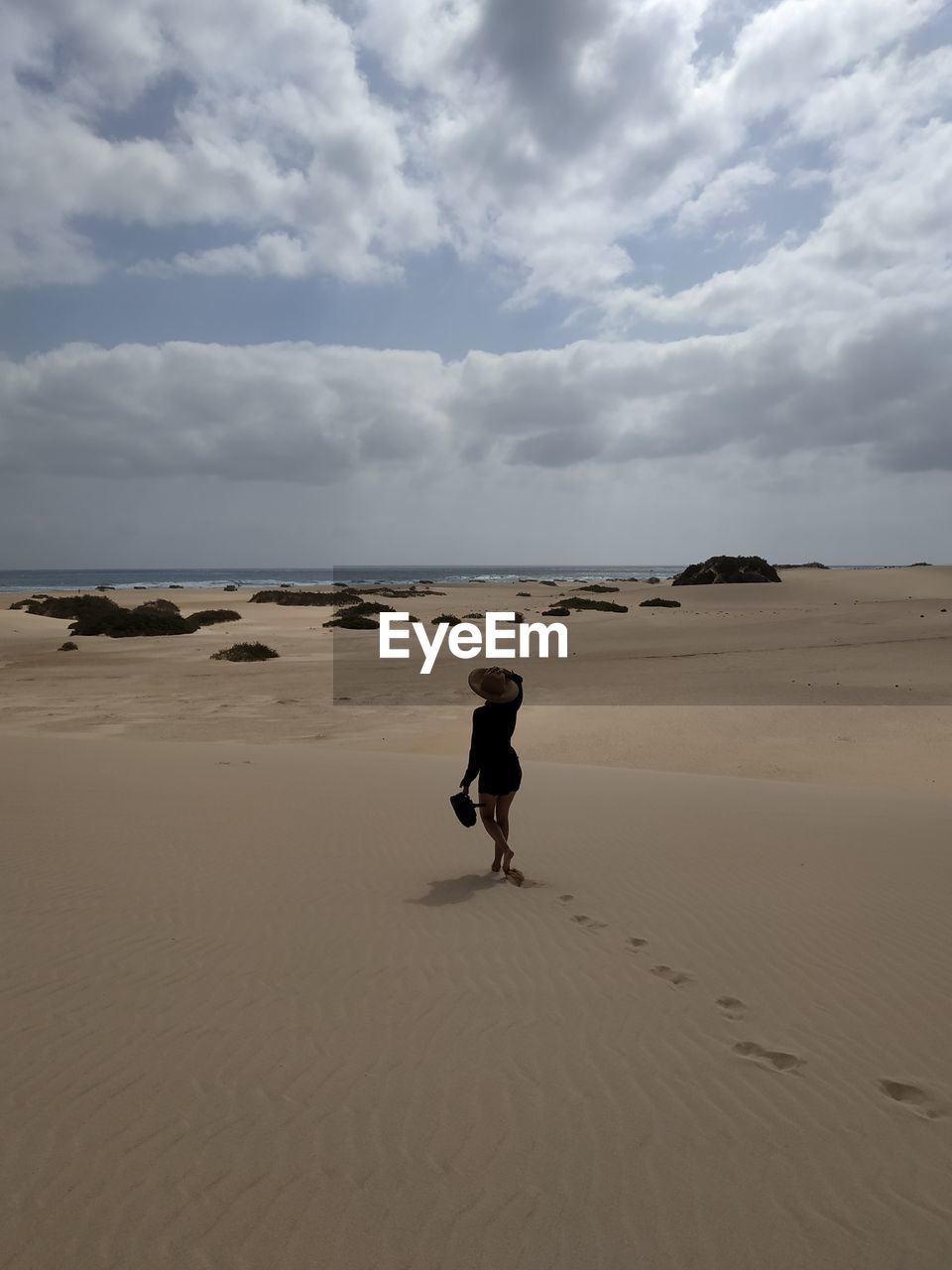 REAR VIEW OF PERSON WALKING ON BEACH
