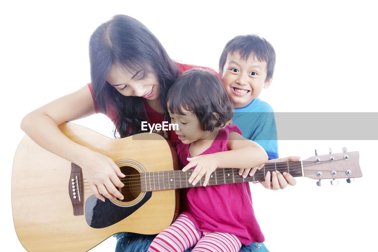 Mother with children playing guitar against white background