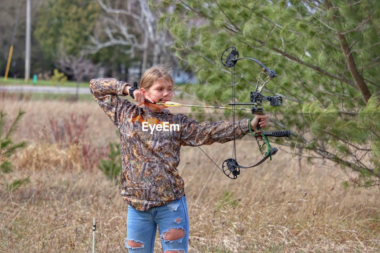 Full length of young lady shooting a bow