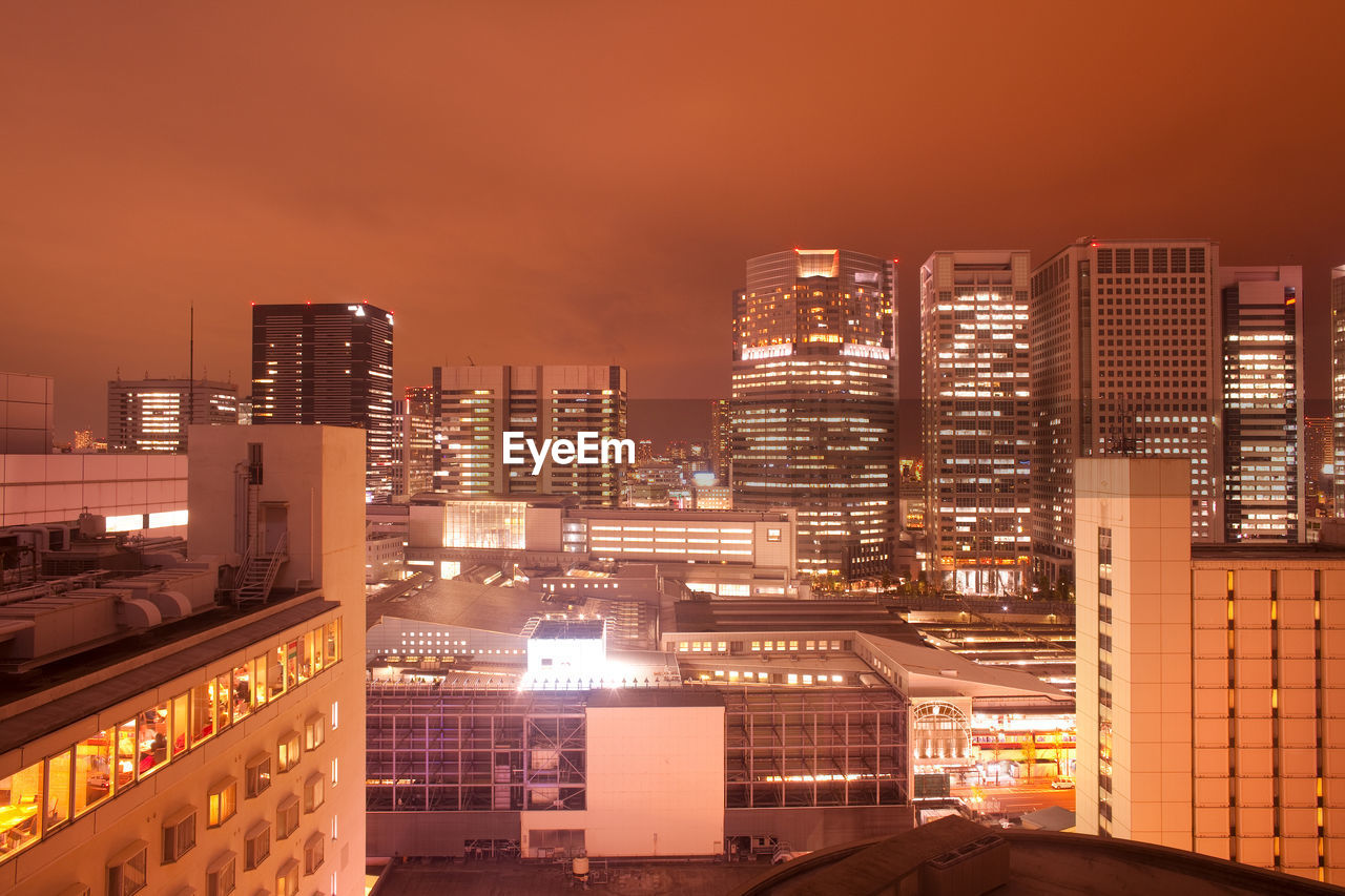 Illuminated buildings in city against sky at night