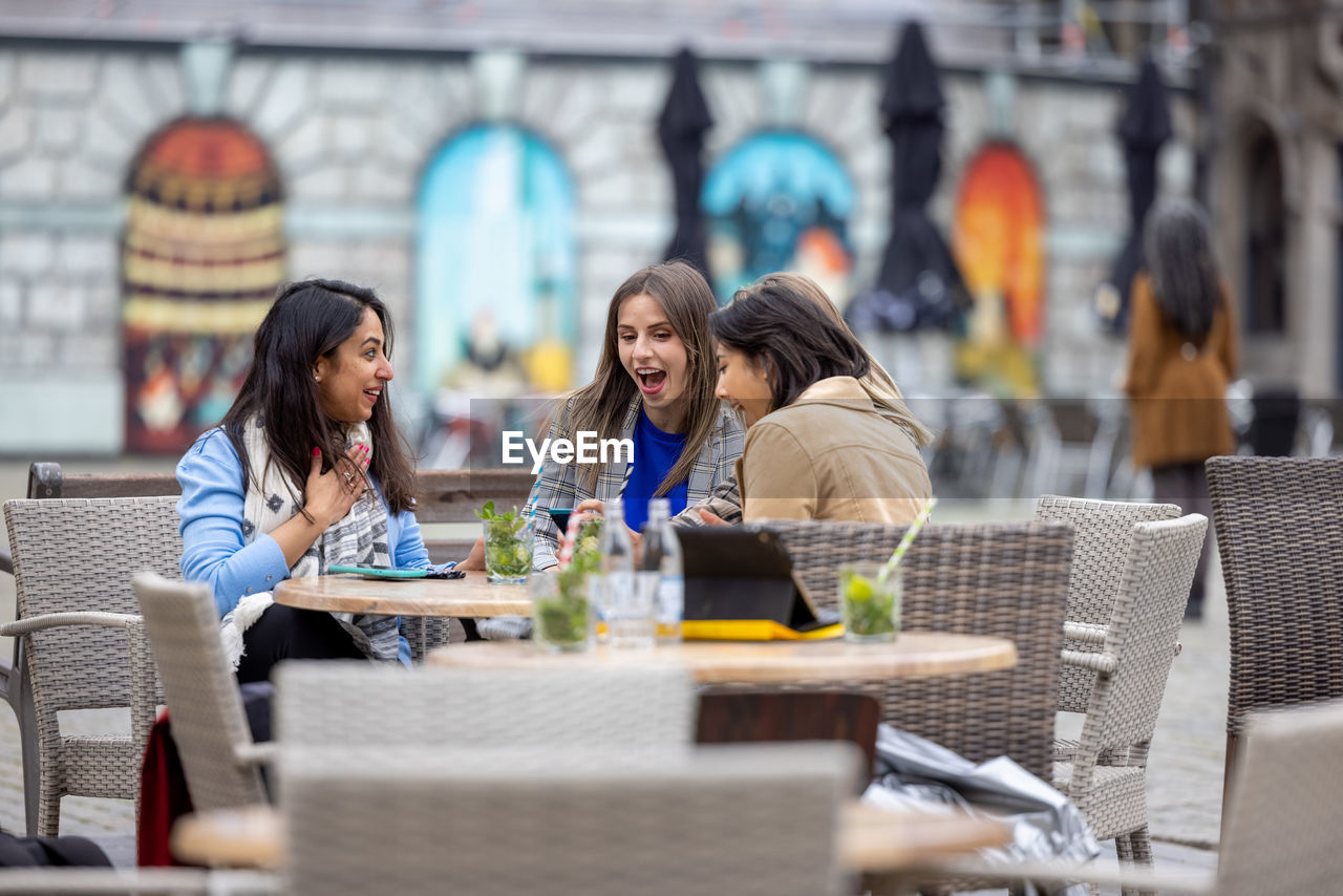 friends using digital tablet while sitting at restaurant