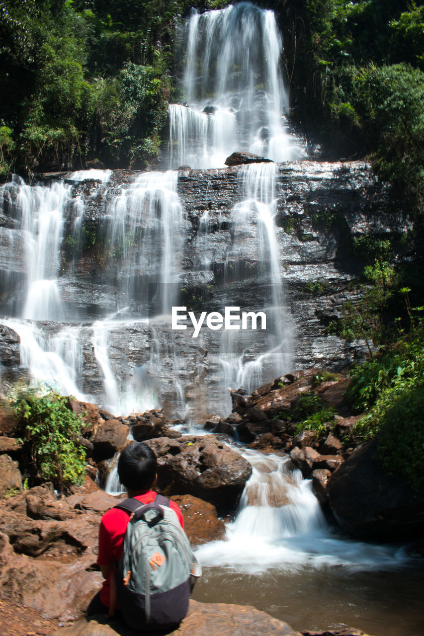 waterfall, water, beauty in nature, scenics - nature, motion, nature, rock, long exposure, tree, forest, plant, flowing water, land, water feature, body of water, environment, tourism, leisure activity, travel destinations, travel, non-urban scene, outdoors, blurred motion, holiday, trip, vacation, sports, one person, lifestyles, activity, rear view, adventure, day, adult, rock formation, men, flowing, river, women