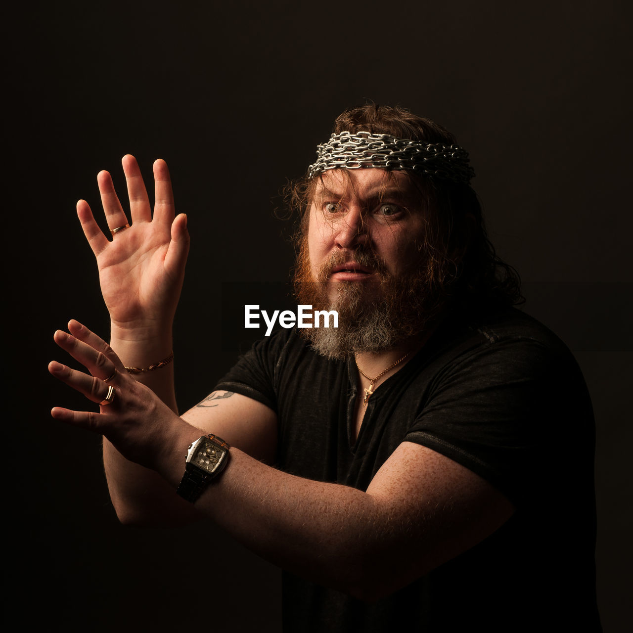 PORTRAIT OF MAN MAKING FACE OVER BLACK BACKGROUND