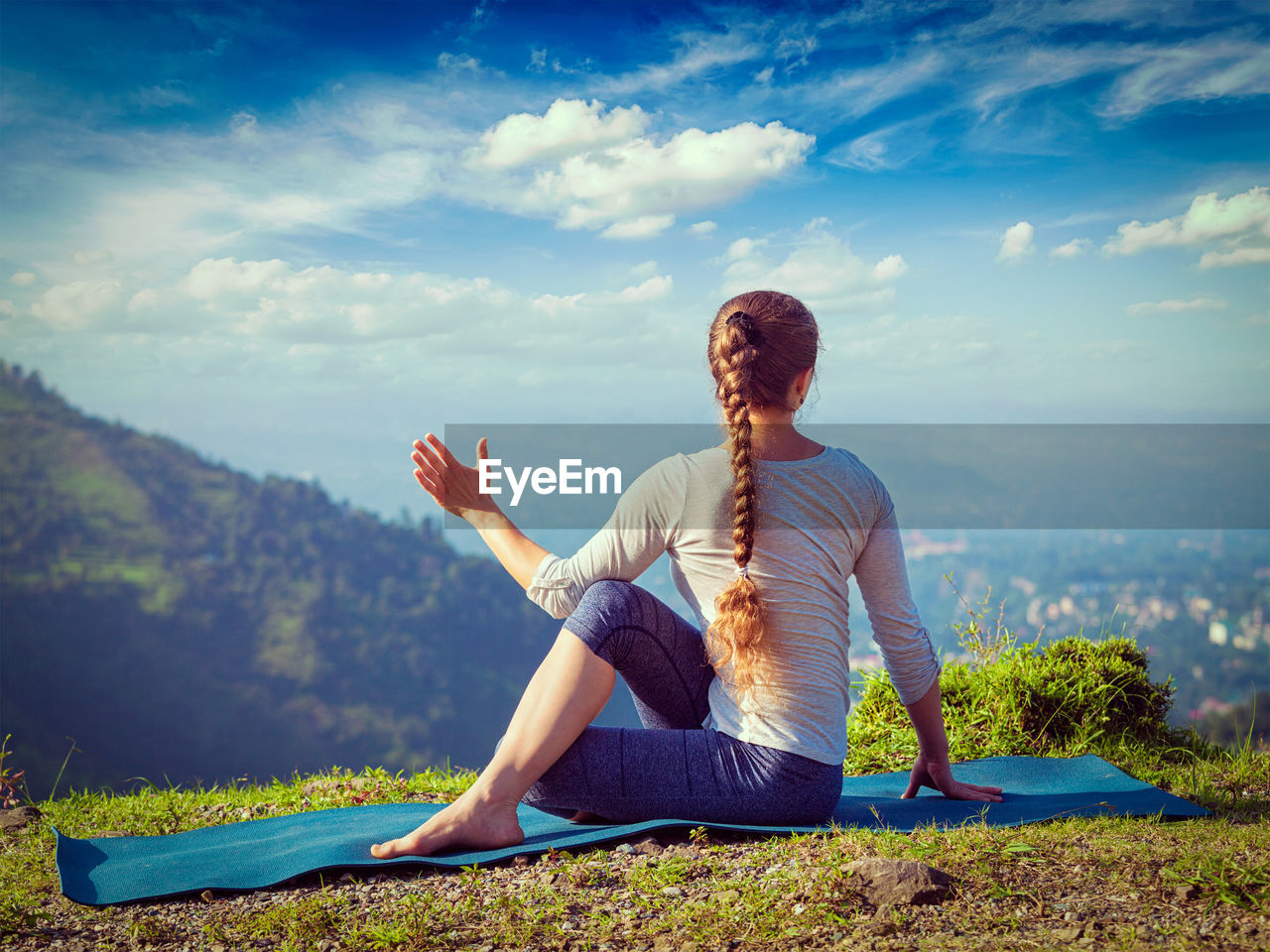 FULL LENGTH OF SENIOR WOMAN SITTING AGAINST MOUNTAIN