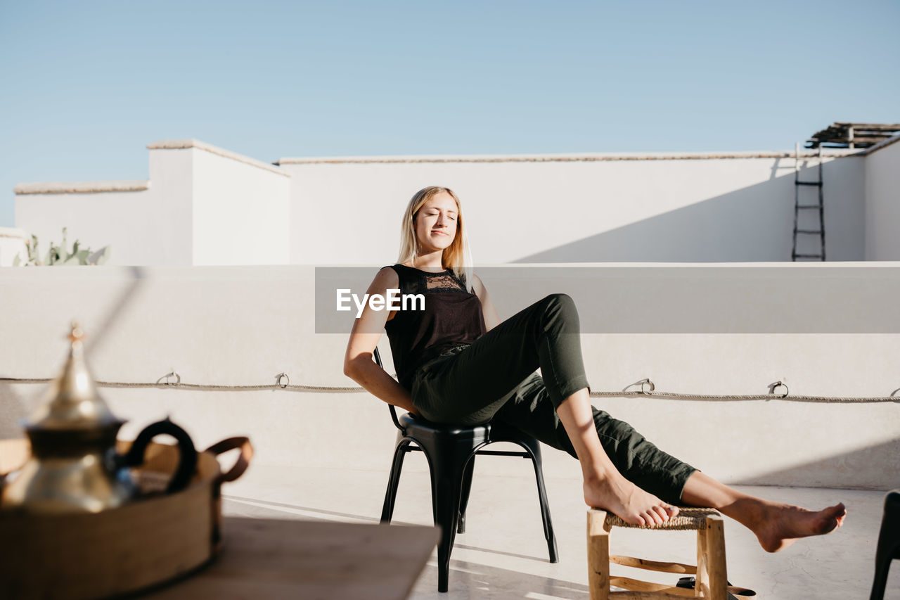 Smiling young woman sitting on chair at building terrace