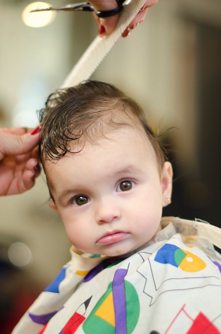 Cropped hand of mother combing baby