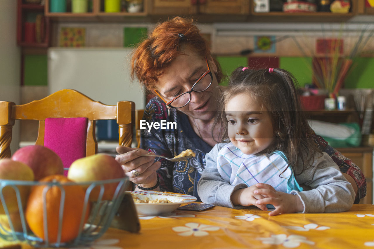 PORTRAIT OF MOTHER AND DAUGHTER ON TABLE AT HOME