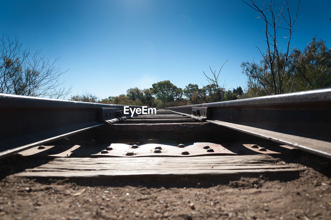 Surface level of railroad tracks against clear blue sky