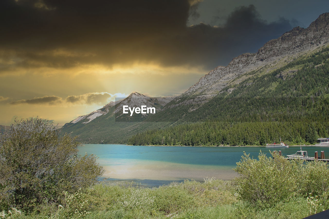 Scenic view of lake and mountains against sky at sunset