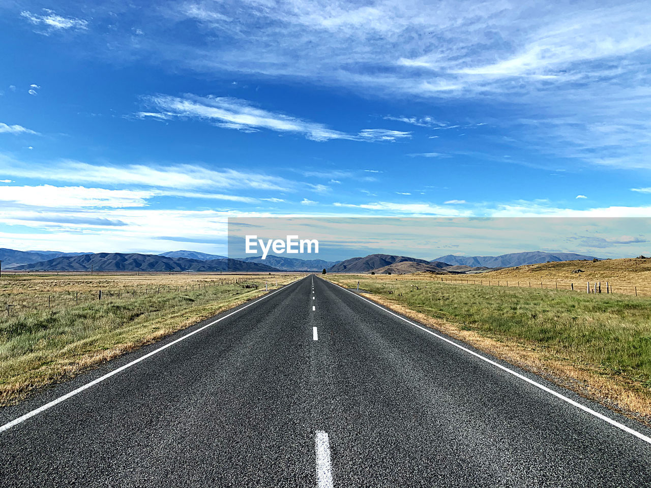 Road leading to distant hills landscape against sky