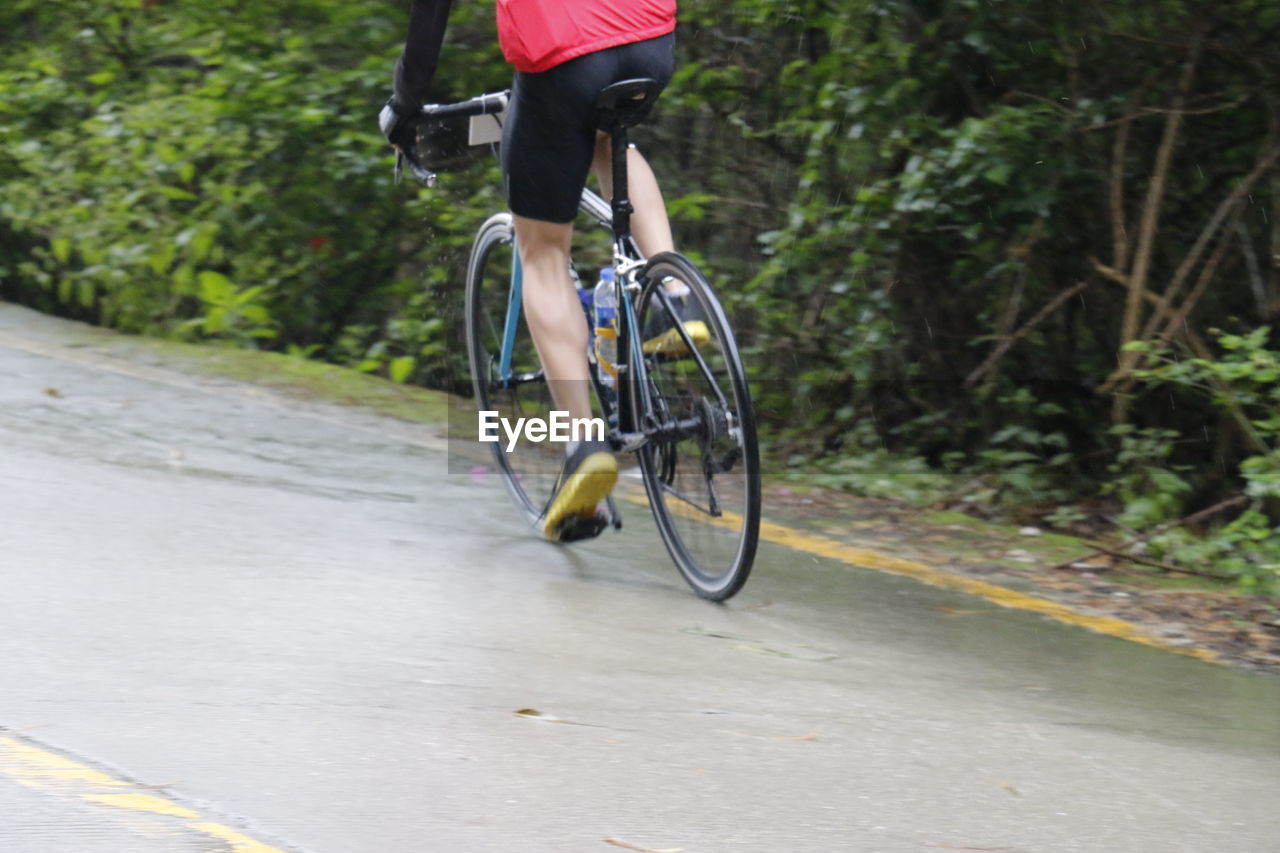 Low section of man riding bicycle on road