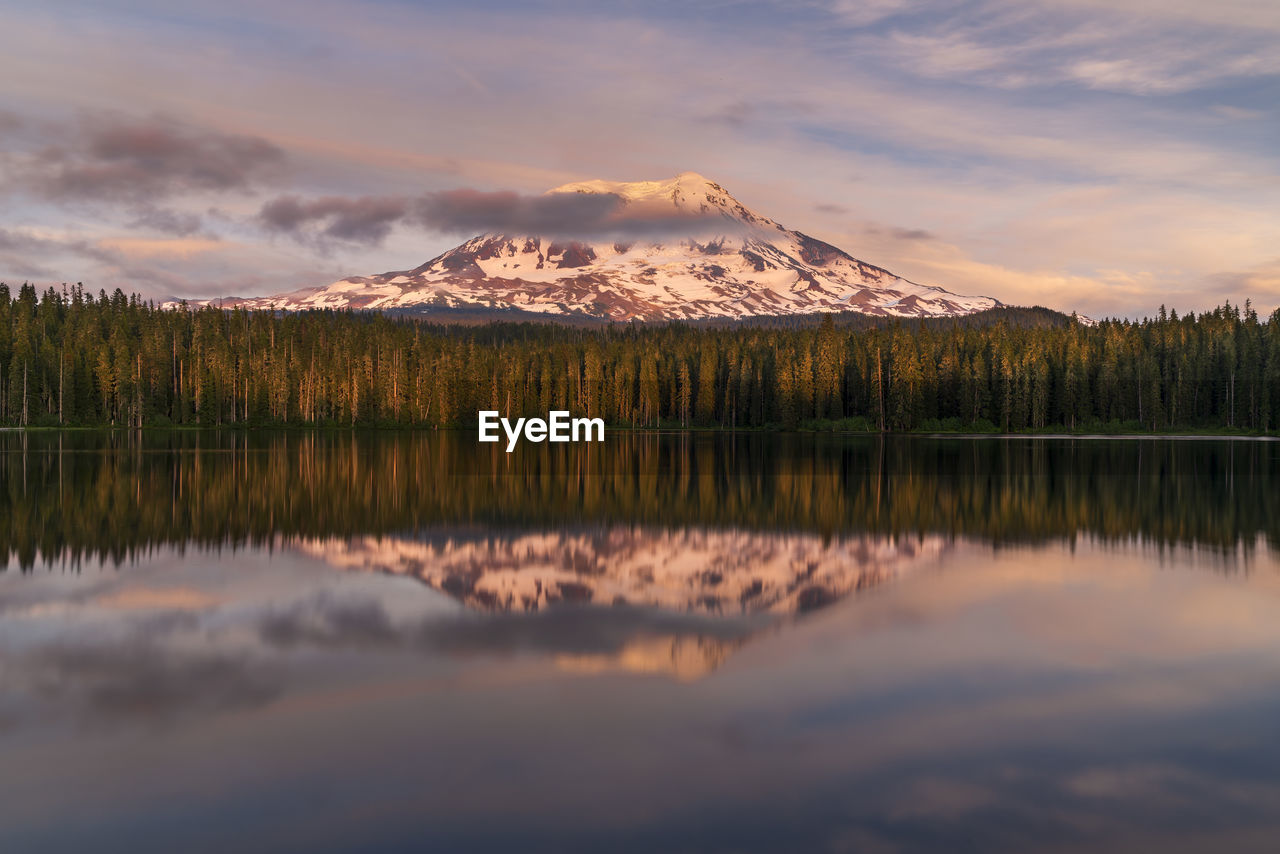 Scenic view of lake by mountains against sky during sunset