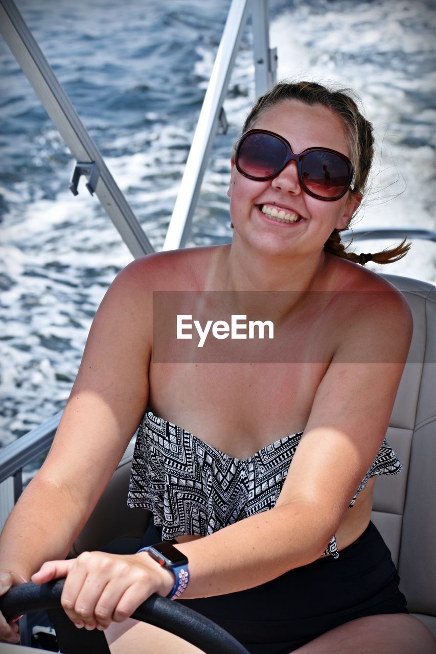 Woman wearing sunglasses sitting in boat on sea