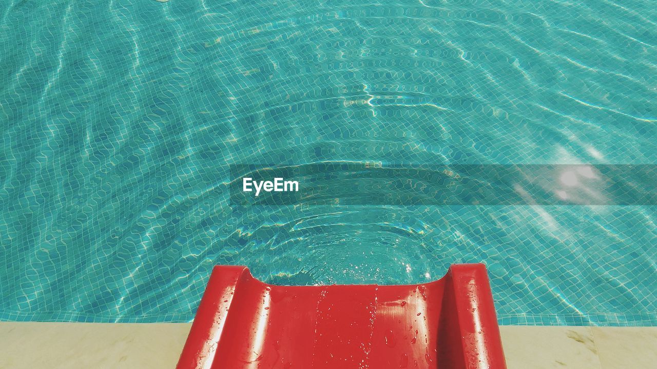 High angle view of red water slide by swimming pool