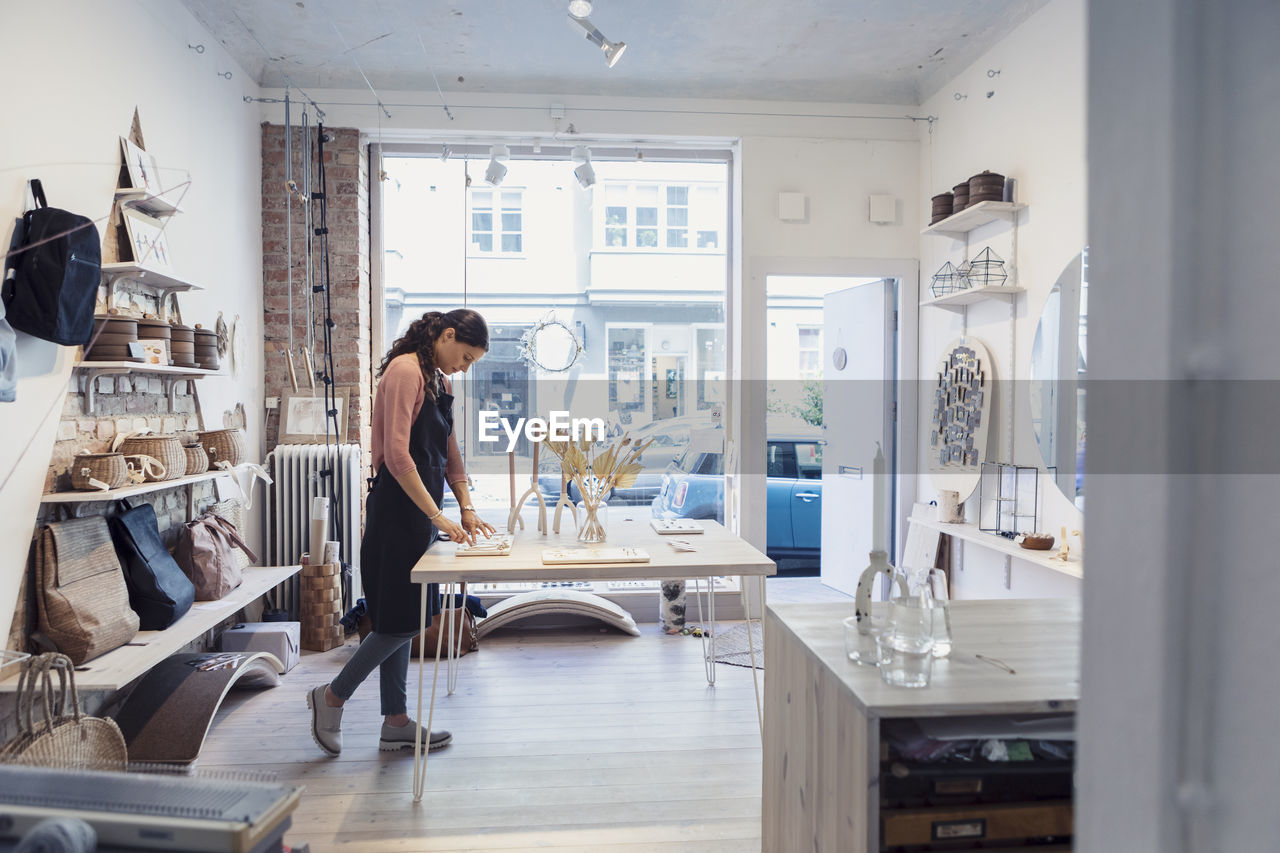 Female owner examining jewelry while standing in design studio