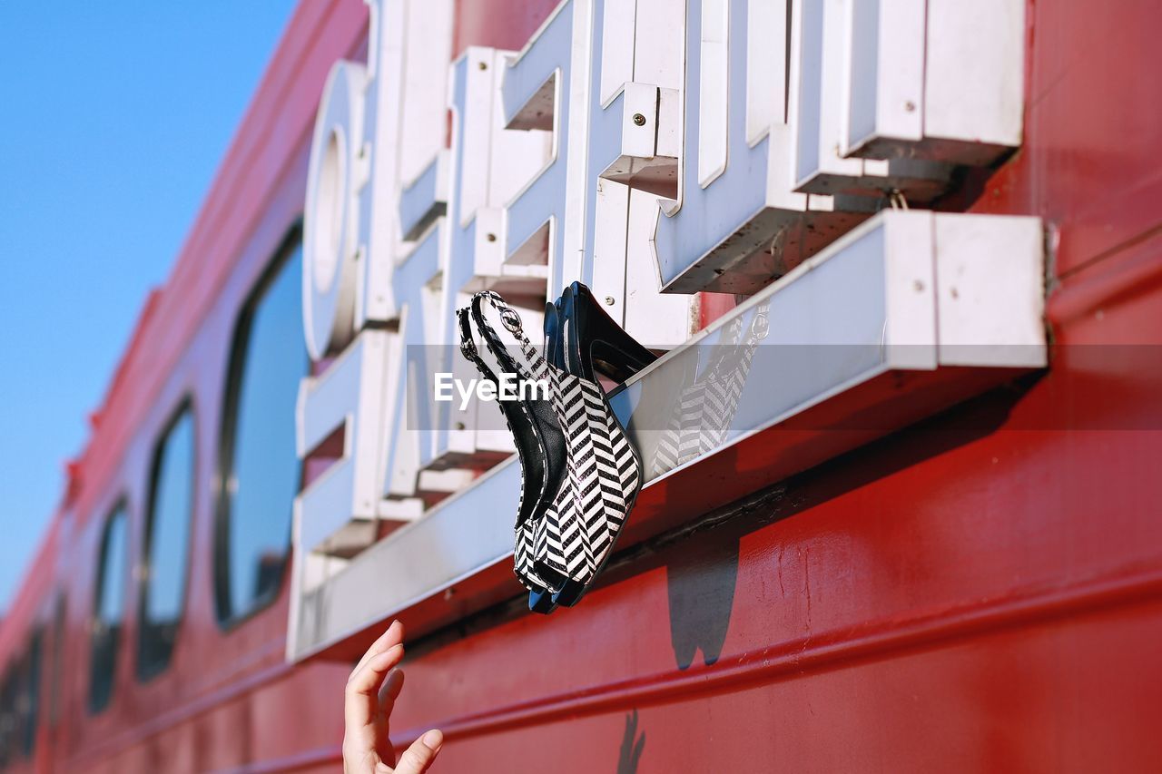 Cropped hand of woman reaching towards high heels stuck on train