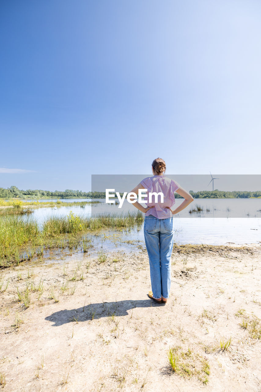 full length of boy standing at beach against clear sky